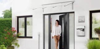 Jakie wybrać drzwi zewnętrzne? Kobieta przed domem