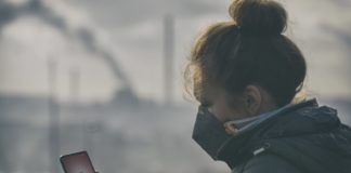 Smog – wielkie wyzwanie współczesności Kobieta w masce antysmogowej sprawdza zanieczyszczenie powietrza