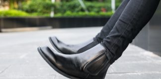 Botki damskie – najmodniejsze buty na tegoroczną jesień Kobieta siedzi w czarnych botkach na murku