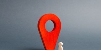 Lokalizatory GPS – kiedy i dlaczego warto z nich korzystać? czerwony wskaźnik lokalizacji i drewniany jasny ludzik