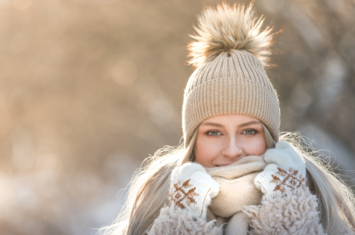 Kobieta w beżowym stroju i czapce z pomponem na zimowym tle
