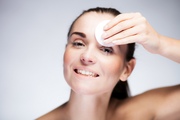 Kobieta oczyszczająca twarz wacikiem nasączonym młynem micelarnym