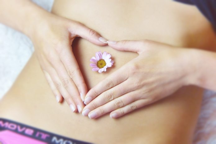 Kobiecy brzuch z kwiatkiem w pępku