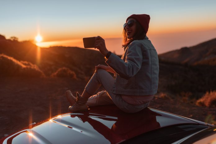 dziewczyna na dachu samochodu filmująca krajobrazy