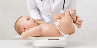 Masa ciała niemowlęcia – jak prawidłowo ocenić rozwój malucha? lekarka ważąca niemowlę na wadze