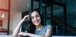 Co zmienić w domu, aby zacząć oddychać lepszym powietrzem? uśmiechnięta szatynka siedząca na kanapie