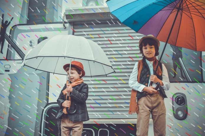 dwaj chłopcy w czasie deszczu pod parasolkami