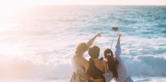 Selfiestick – czym jest i do czego służy? dziewczyny nad morzem robiące selfie przy pomocy selfiesticka