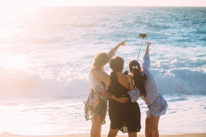 dziewczyny nad morzem robiące selfie przy pomocy selfiesticka