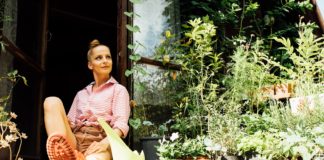 Na co zwrócić uwagę kupując działkę? kobieta w kaloszach siedząca w drzwiach domku na działce