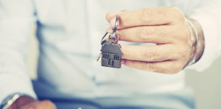 Jak bezpiecznie wynająć dom lub mieszkanie? wyciągnięta męska dłoń trzymająca klucze do mieszkania