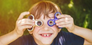 Czym jest ADHD oraz jak wcześnie rozpoznać jego objawy w procesie rozwoju dziecka? zadowolony chłopiec ze spinnerami