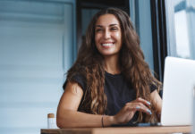 Działaj online! Czyli jakie ważne sprawy załatwisz, nie wychodząc z domu? piękna uśmiechnięta kobieta z długimi włosami przed laptopem