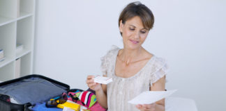 Niezbędnik w podróży – co spakować na wyjazd? kobieta pakująca apteczkę do walizki