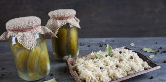 Odkryj niezwykłą moc zakwasów warzywnych Surówka z kiszonej kapusty na drewnianej tacy, kiszone ogórki w słoikach