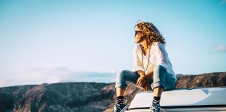 Czy w Polsce opłaca się podróżować kamperem? kobieta na wakacjach na dachu kampera