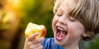 Jak zadbać o zdrowie dziecka? chłopiec jedzący jabłko