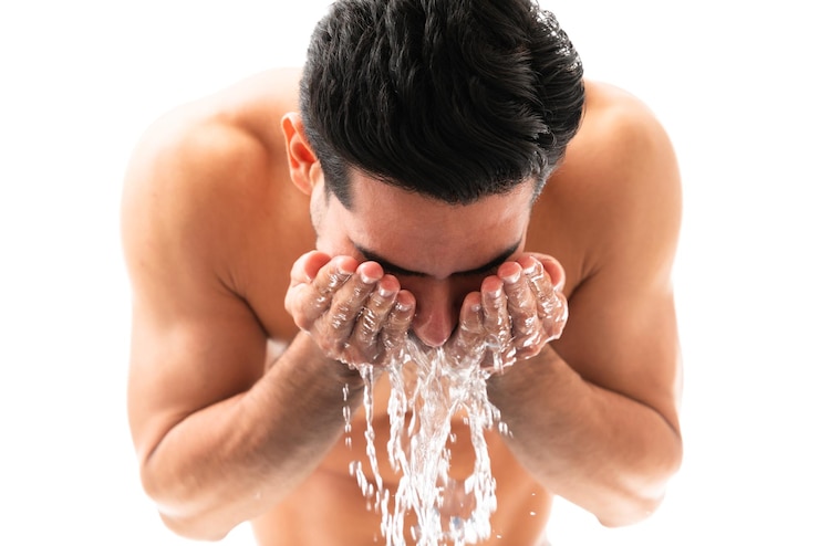 Mężczyzna jest pochylany, myje twarz wodą. Czym mężczyzna powinien myć twarz?